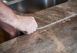 A worker is installing a granite countertop and showing the seam.