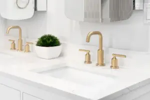 Double sinks with gold faucets and a white marble countertop in a Springville, UT bathroom 