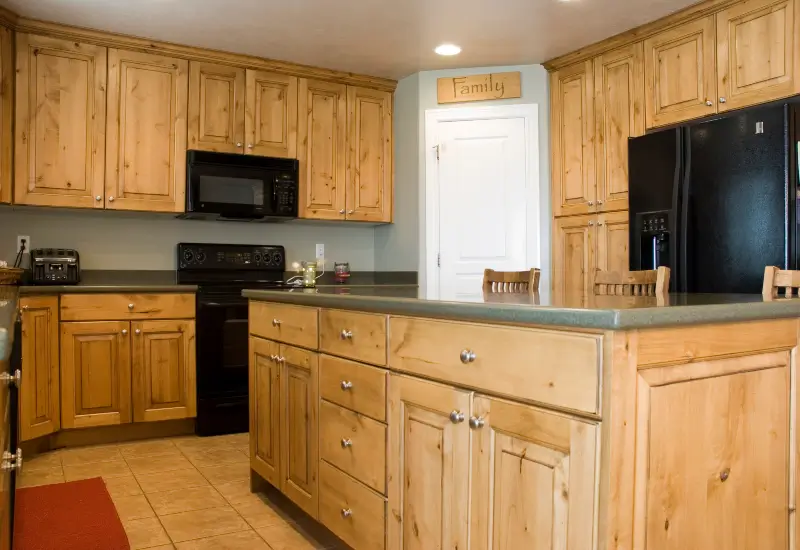 A quartz countertop in a Springville, UT kitchen with hickory cabinets and black appliances.